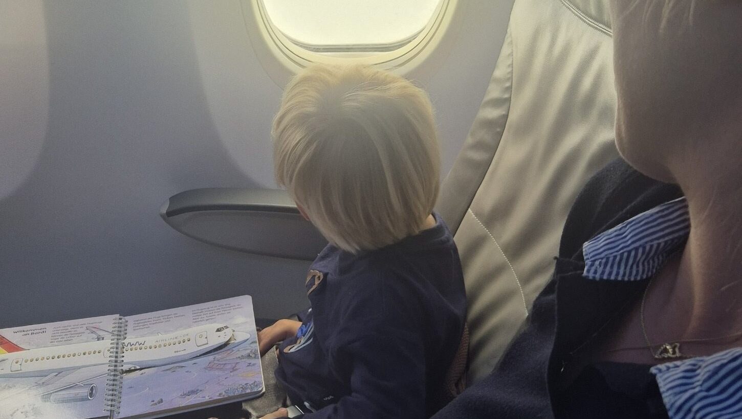 Finn mit Bilderbuch im Flugzeug neben Sabrina