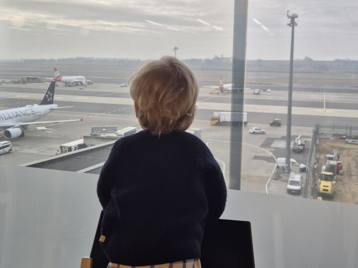 Finn schaut am Flughafen aus dem Fenster auf die Flugzeuge